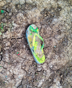 photograph of a flip flop with multicolored spray in the mud at Cadillac Ranch